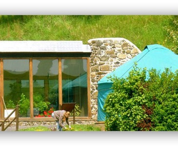 Photo of a worker in front of Earthship Fife and the yurt
